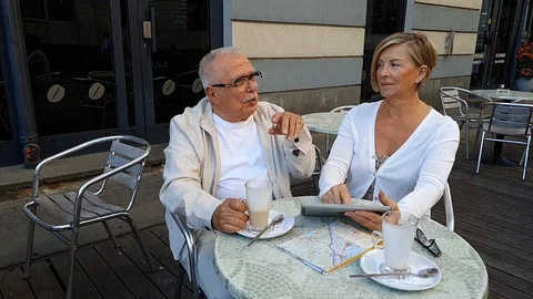 Laughing elderly couple sit at grey circular tesselate table Stock Footage 127182413