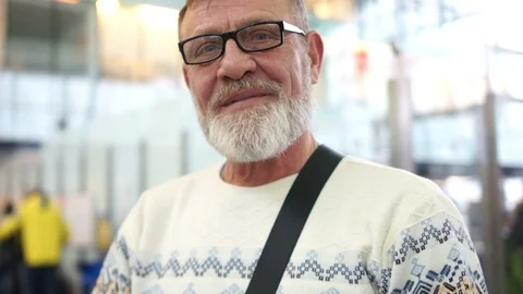 Laughing elderly man with glasses and a gray beard at the airport. Close Stock Footage 101180564