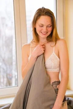 Laughing girl in bra wake up and make up bed Stock Photos