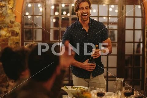 Laughing man opening champagne at party Stock Photos