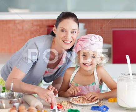 Laughing mother and her daughter baking in a kitchen Stock Photos