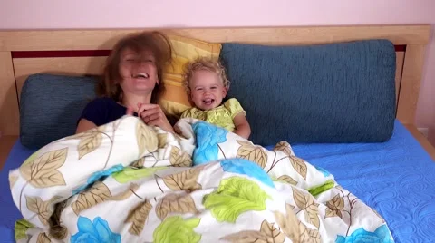 Laughing mother with toddler girl playing in bed Stock Footage