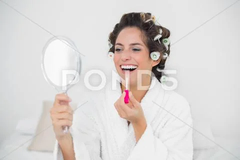 Laughing natural brunette putting lip gloss on Stock Photos