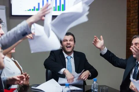 Laughing people at table throwing papers Stock Photos