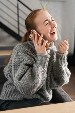 Laughing redhead sitting on the couch having a conversation on the phone at home Stock Photos