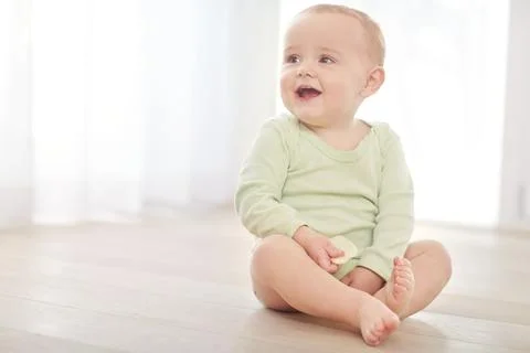 Laughing, teething biscuit and thinking with baby on living room floor for .. Stock Photos