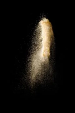 Launch brown particles exploding on black background. Brown dust splashing. Stock Photos