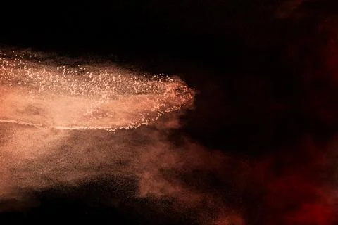 Launch brown particles exploding on black background. Brown dust splashing. Stock Photos