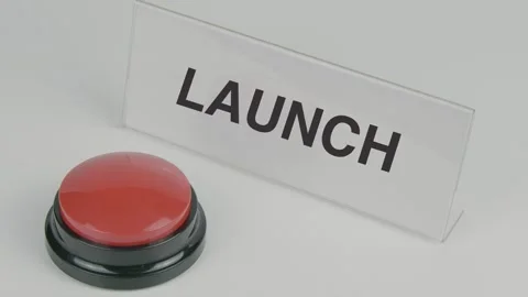 Launch text or word displayed on a nameplate as a hand presses a red button Stock Footage 307196593