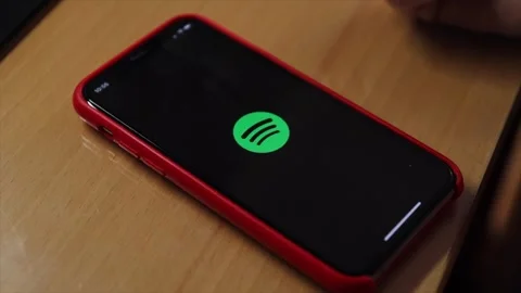Launching the Spotify app on a smartphone with a red case Stock Footage 304067935