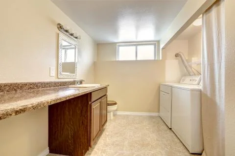 Laundry and bathroom interior in soft tones with tile floor, white appliances Stock Photos