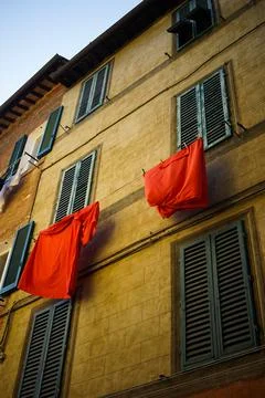 Laundry and bed sheets hang from italian building Stock Photos