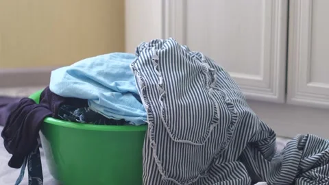 Laundry and house cleaning theme. Dirty laundry items for washing are thrown int Stock Footage 191107088