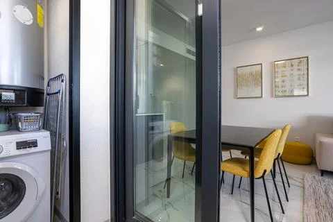 Laundry area with washing machine next to modern dining space Stock Photos
