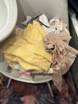 Laundry Basin Full of Clothes and Towels on a Chair Stock Photos