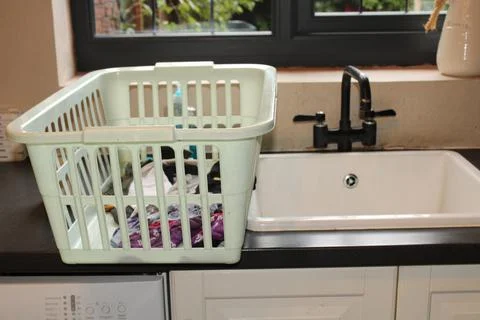 Laundry basket by the kitchen sink Stock Photos
