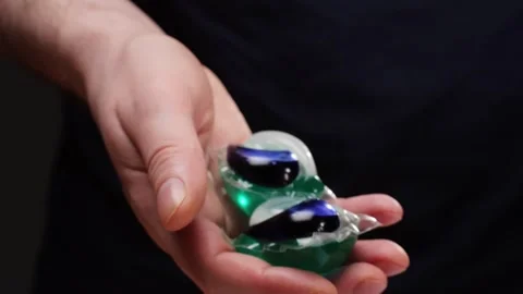 Laundry capsules for washing machine in man hands close-up. capsule contains Video stock 270009796