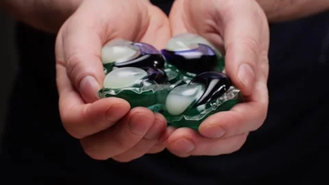 Laundry capsules for washing machine in man hands close-up. capsule contains Stock Footage 270186562