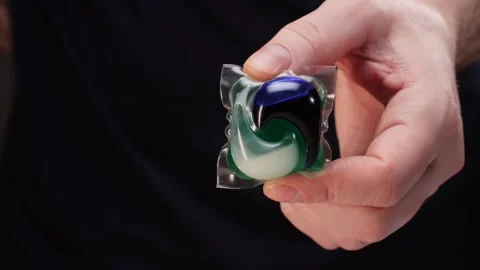 Laundry capsules for washing machine in man hands close-up. capsule contains Stock Footage 270479346