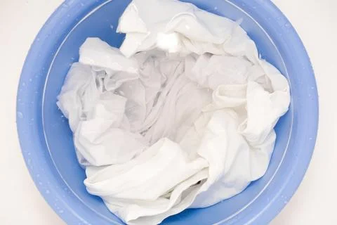 Laundry concept with Soak white clothes close up in blue bowl prepared for hand Stock Photos