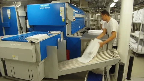 Laundry crew arranging clean folded sheets from machine on rack at cruise ship Video stock 117751085