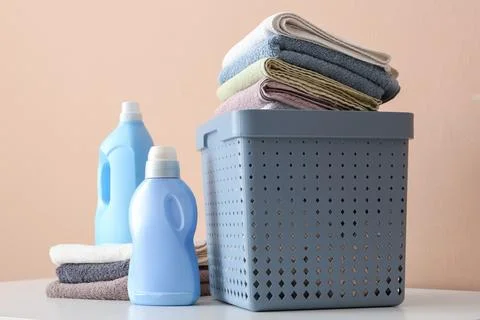 Laundry day essentials: stack of clean towels, detergent, and fabric softener Stock Photos