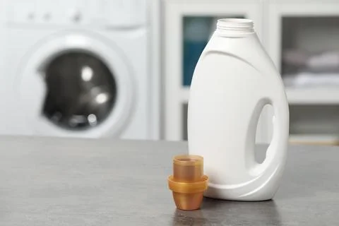 Laundry detergent and cap on grey table, space for text Stock Photos