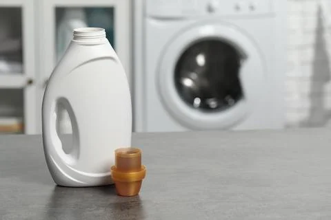 Laundry detergent and cap on grey table, space for text Stock Photos