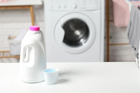 Laundry detergent and cap on white table in bathroom, space for text Stock Photos
