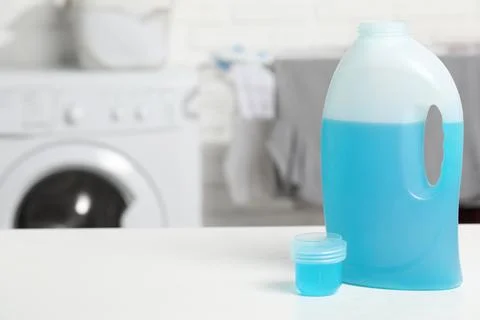 Laundry detergent and cap on white table in bathroom, space for text Stock Photos