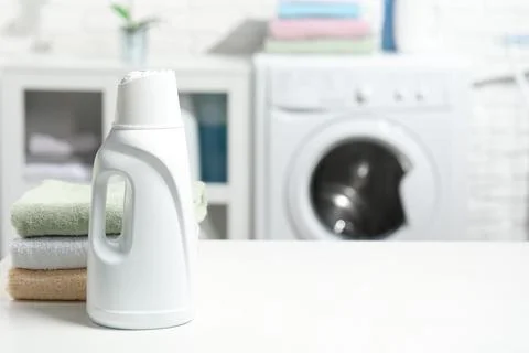 Laundry detergent and stacked clean towels on white table, space for text Stock Photos