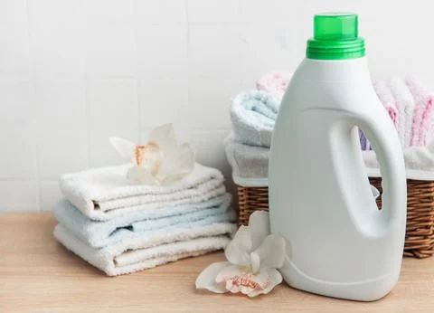 Laundry detergent bottle with fresh clean towels and orchids Stock Photos