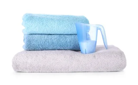 Laundry detergent in plastic measuring cup and towels on white background Stock Photos