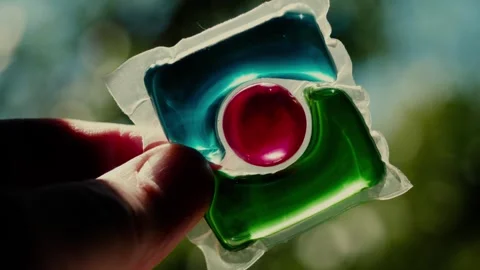 Laundry detergent pod. Men hand holds colorful water soluble sachet. Liquitabs. Stock Footage 277536239