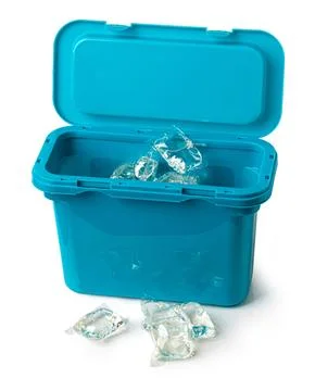 Laundry detergent pods spilling from blue container on white background Stock Photos