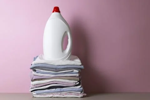Laundry Detergents, stack of clothes and Washing Supplies on color Background Fotos Stock