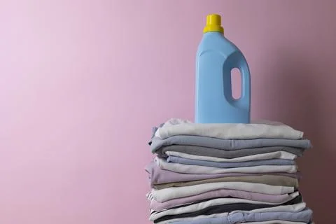 Laundry Detergents, stack of clothes and Washing Supplies on color Background Fotos Stock