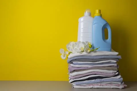 Laundry Detergents, stack of clothes and Washing Supplies on color Background Fotos Stock