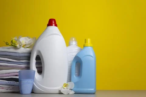 Laundry Detergents, stack of clothes and Washing Supplies on color Background Fotos Stock