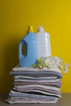 Laundry Detergents, stack of clothes and Washing Supplies on color Background Fotos Stock