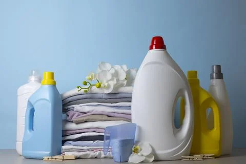 Laundry Detergents, stack of clothes and Washing Supplies on color Background Fotos Stock