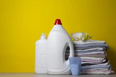 Laundry Detergents, stack of clothes and Washing Supplies on color Background Fotos Stock