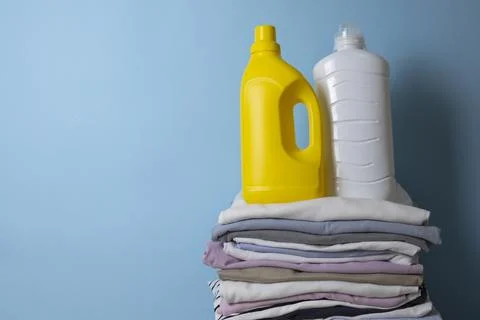 Laundry Detergents, stack of clothes and Washing Supplies on color Background Fotos Stock