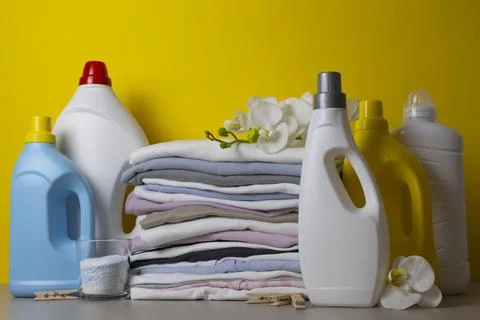 Laundry Detergents, stack of clothes and Washing Supplies on color Background Fotos Stock