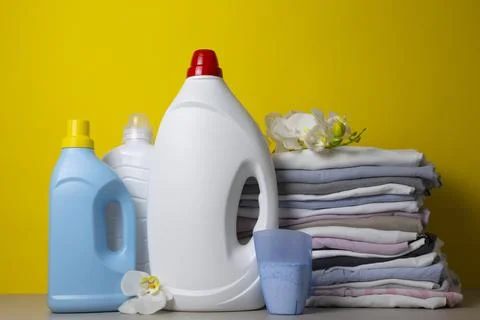 Laundry Detergents, stack of clothes and Washing Supplies on color Background Fotos Stock