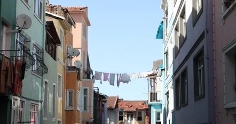 Laundry hanging between colorful homes under clear blue sky Stock Footage 321047529