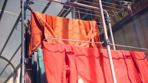 Laundry hanging from drying rack outside in the sun and wind Stock Footage 129315542