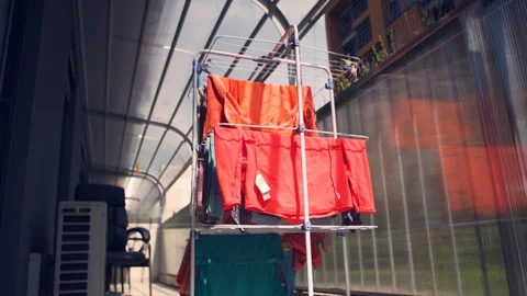 Laundry hanging from drying rack outside in the sun and wind Stock Footage 129319170