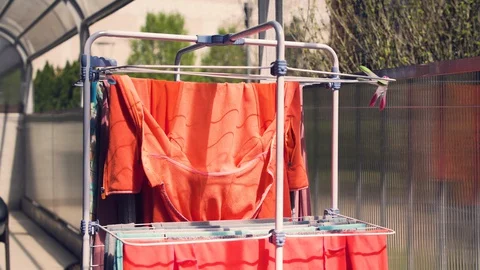 Laundry hanging from drying rack outside in the sun and wind Stock Footage 129319511