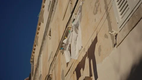 Laundry hanging from an old building in a sunlit neighborhood of Dubrovnik old Stock Footage 296013943